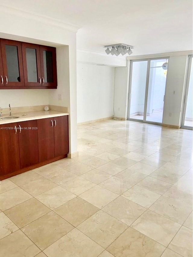 kitchen featuring sink, a wall of windows, and ornamental molding