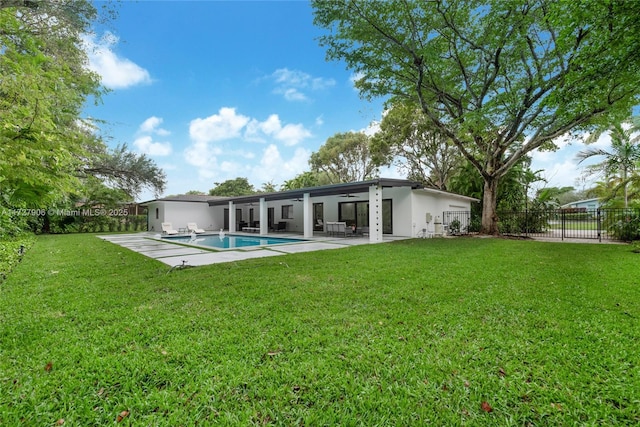 rear view of house with ceiling fan, a yard, a fenced in pool, and a patio area