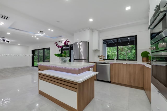 kitchen featuring white cabinetry, ceiling fan, stainless steel appliances, and a center island