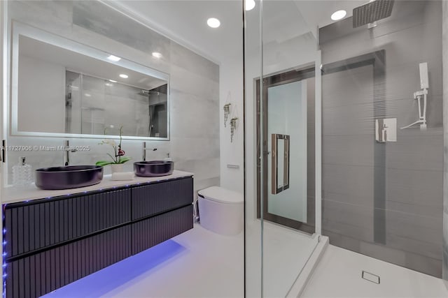 bathroom with tile walls, vanity, a shower with door, and toilet