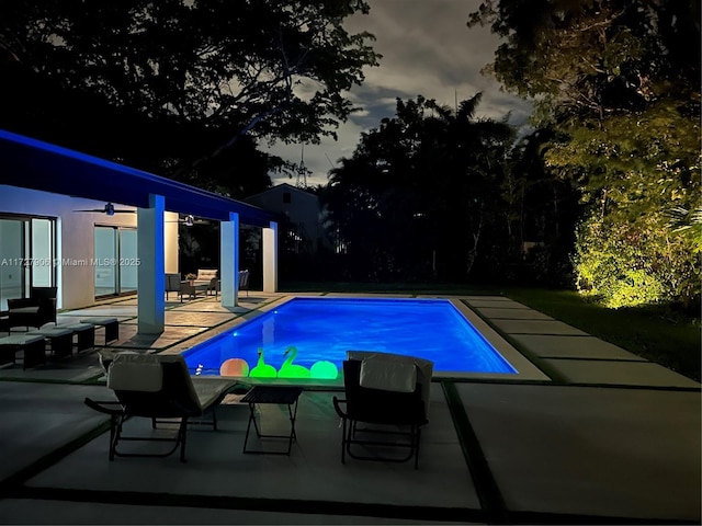 pool at dusk featuring a patio