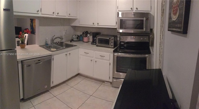 kitchen with light tile patterned floors, stainless steel appliances, white cabinets, and sink