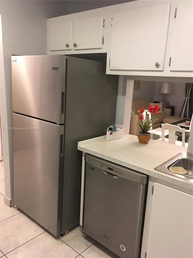 kitchen featuring sink, light tile patterned floors, white cabinets, and stainless steel appliances