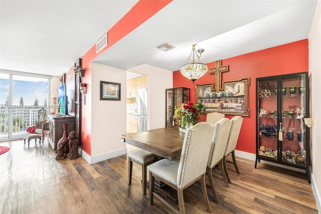 dining space with a wall of windows, dark hardwood / wood-style floors, and an inviting chandelier