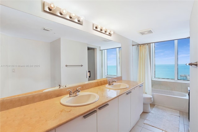 bathroom featuring a bathing tub, tile patterned flooring, vanity, toilet, and a water view