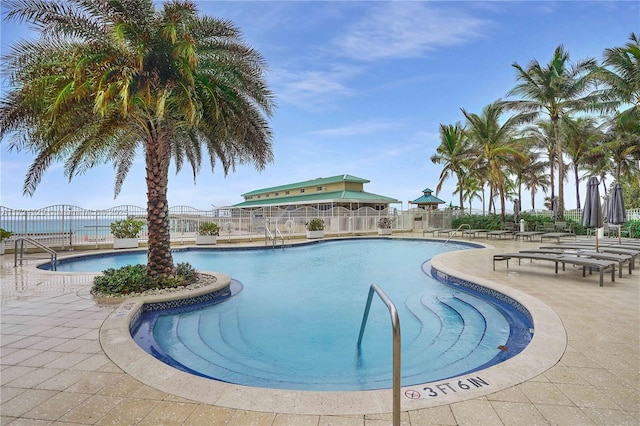 view of pool featuring a water view and a patio area