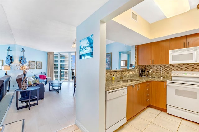 kitchen featuring decorative backsplash, sink, white appliances, and light stone countertops