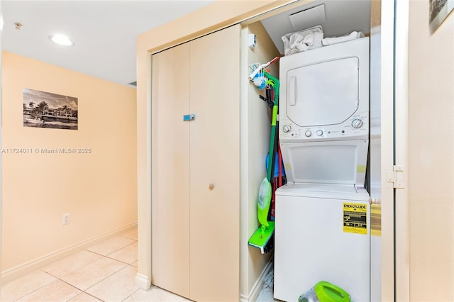 laundry area featuring light tile patterned flooring and stacked washer / dryer