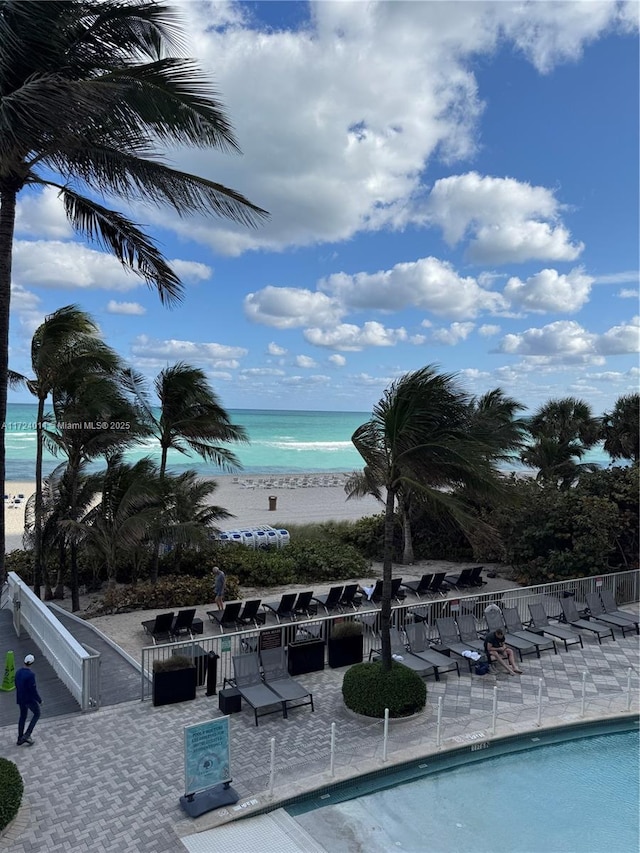 view of swimming pool with a water view and a view of the beach