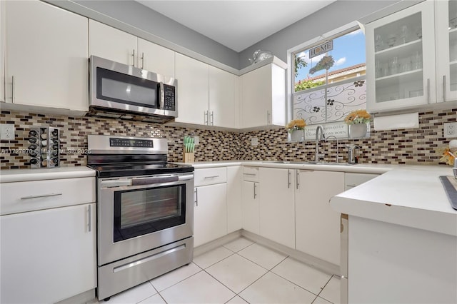 kitchen with decorative backsplash, white cabinets, and appliances with stainless steel finishes