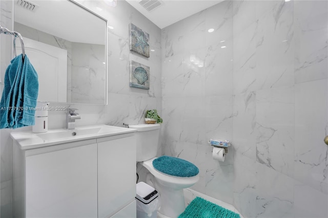 bathroom with toilet, tile walls, and vanity