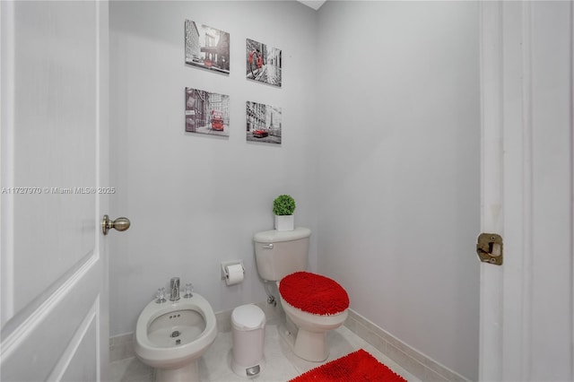 bathroom featuring toilet, a bidet, and tile patterned floors