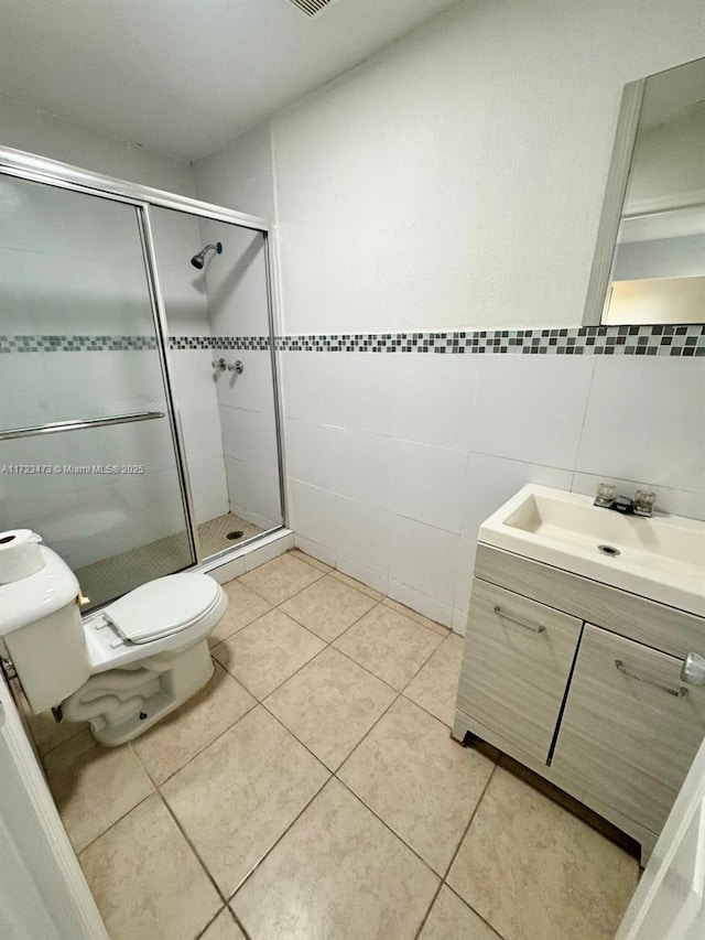 bathroom featuring toilet, tile patterned flooring, tile walls, an enclosed shower, and vanity