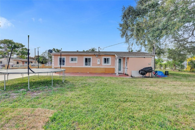 back of property featuring a yard and a trampoline