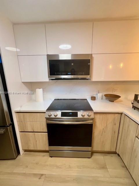 kitchen featuring light brown cabinets, appliances with stainless steel finishes, and light hardwood / wood-style flooring