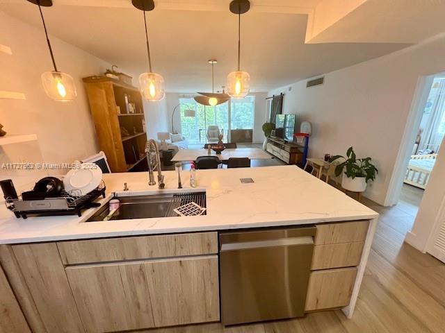 kitchen featuring sink, stainless steel dishwasher, pendant lighting, and light brown cabinetry