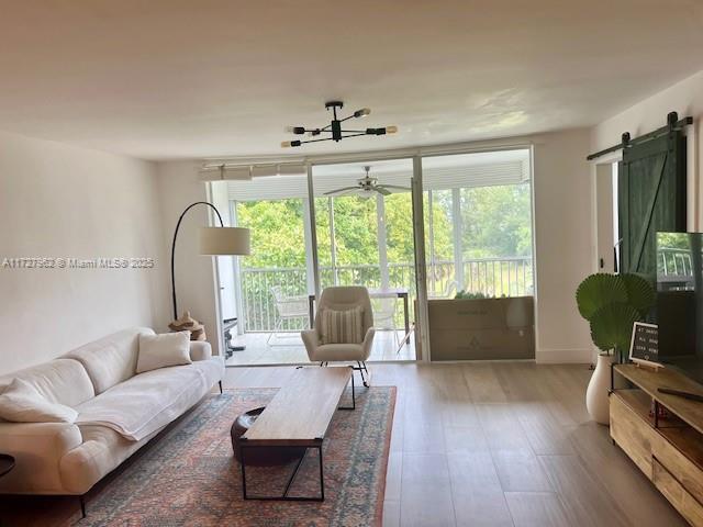 living room featuring plenty of natural light, hardwood / wood-style flooring, ceiling fan, and a barn door