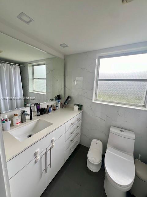 bathroom featuring plenty of natural light, toilet, and vanity