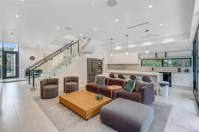 living room with sink, light wood-type flooring, and a wealth of natural light