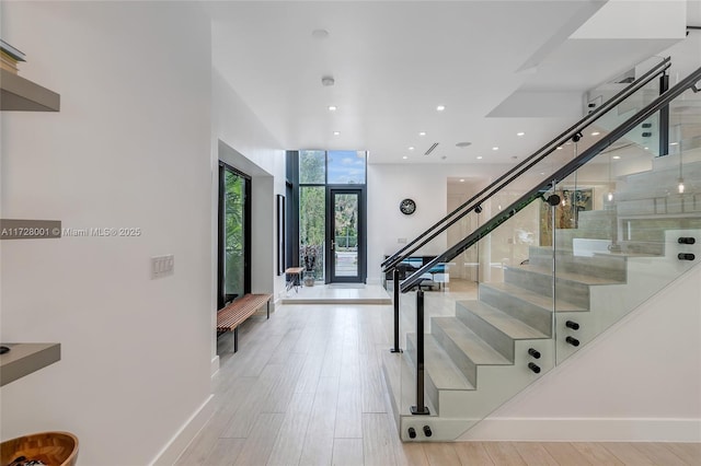 stairway featuring wood-type flooring, expansive windows, and french doors