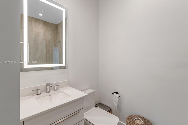 bathroom featuring vanity, toilet, and tiled shower