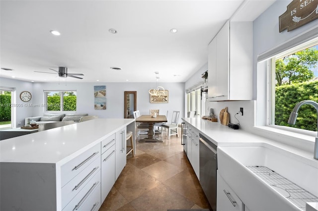 kitchen featuring white cabinetry, ceiling fan, a kitchen island, stainless steel dishwasher, and sink