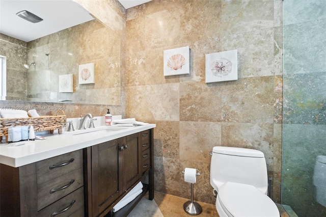 bathroom featuring tile walls, toilet, vanity, and walk in shower