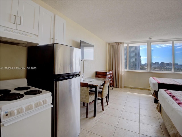 kitchen featuring light tile patterned floors, stainless steel refrigerator, a textured ceiling, white electric stove, and white cabinets