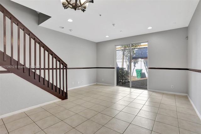 spare room with light tile patterned floors and an inviting chandelier