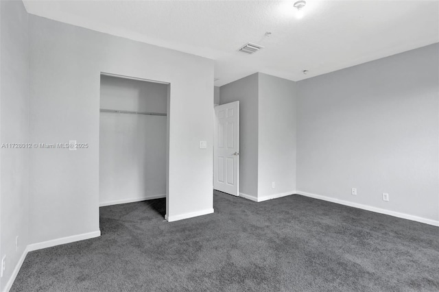 unfurnished bedroom featuring a closet and dark carpet