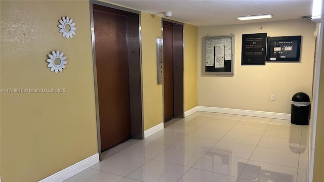 hall featuring light tile patterned flooring and elevator