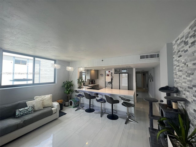 interior space with kitchen peninsula, stainless steel fridge, a breakfast bar area, black electric cooktop, and sink