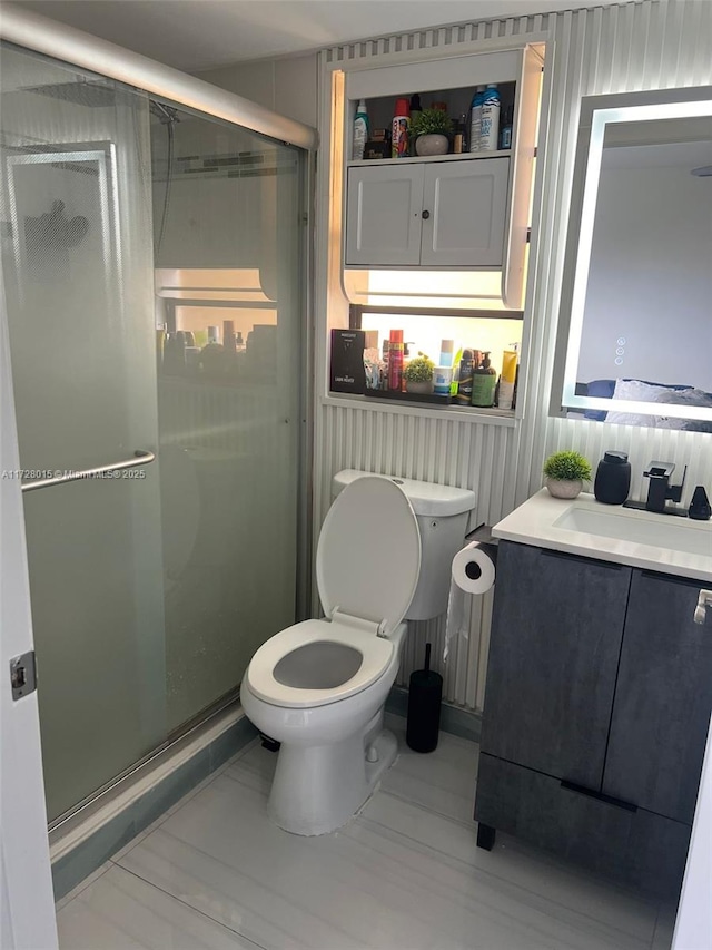 bathroom with toilet, vanity, and a shower with door