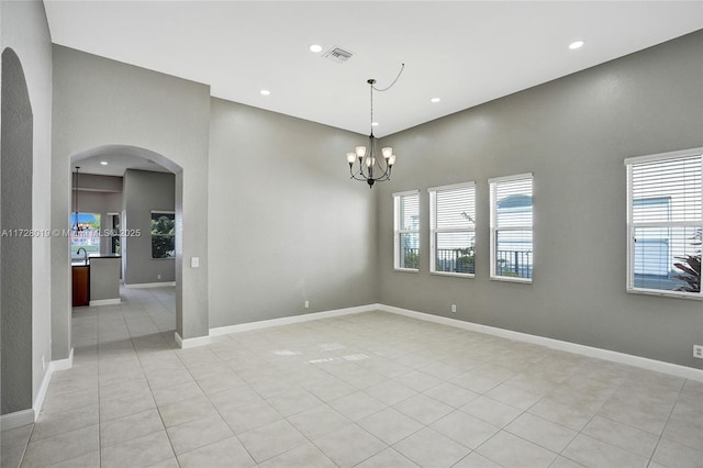 tiled empty room with a notable chandelier, sink, and a high ceiling