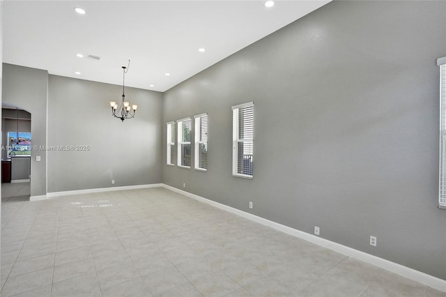 spare room featuring light tile patterned flooring and a chandelier