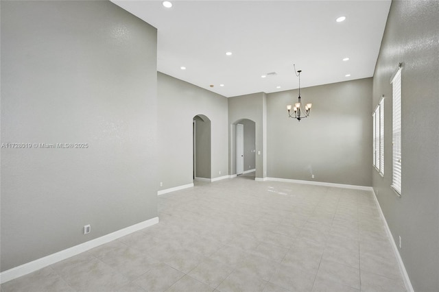 tiled empty room with a high ceiling and a notable chandelier