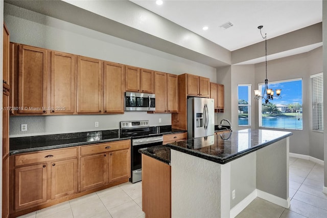 kitchen featuring decorative light fixtures, a notable chandelier, a kitchen island with sink, stainless steel appliances, and dark stone counters