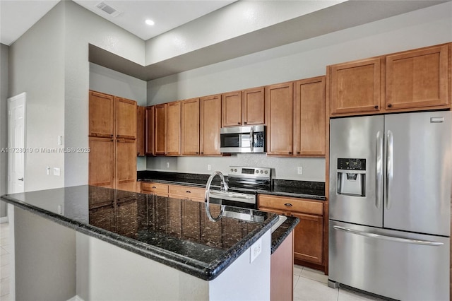 kitchen with appliances with stainless steel finishes, dark stone counters, and light tile patterned flooring