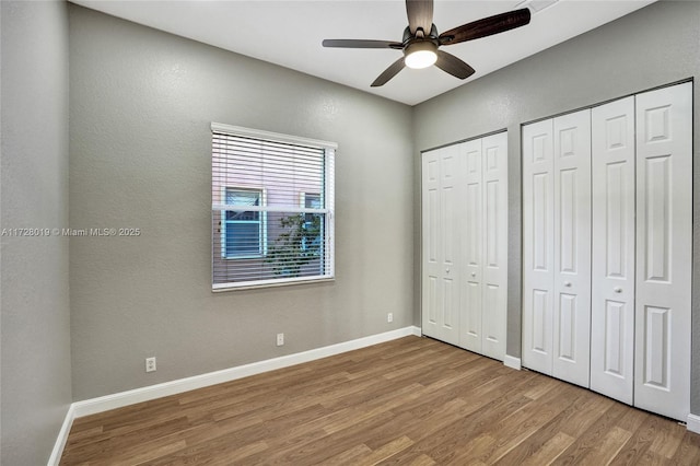 unfurnished bedroom with ceiling fan, two closets, and light hardwood / wood-style floors