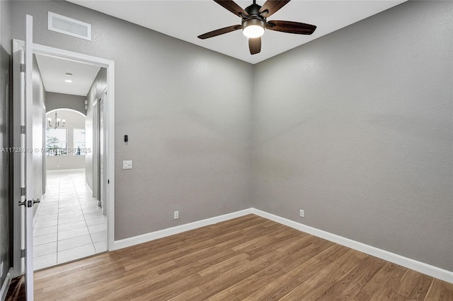 unfurnished room featuring ceiling fan with notable chandelier and wood-type flooring