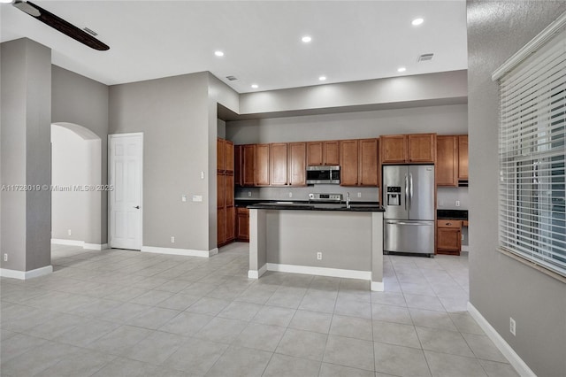 kitchen featuring light tile patterned floors, appliances with stainless steel finishes, a towering ceiling, and a center island