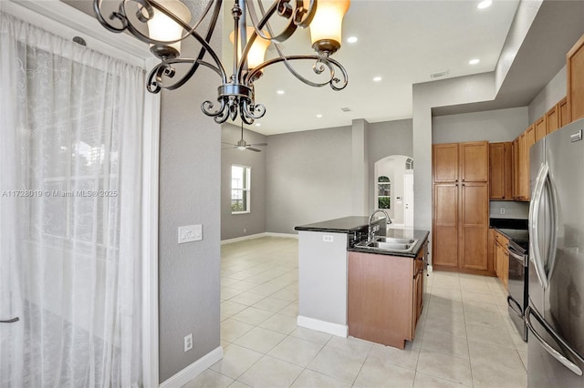 kitchen with stainless steel fridge, a kitchen island with sink, electric range oven, ceiling fan with notable chandelier, and sink