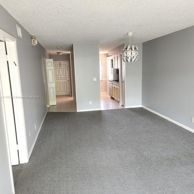 unfurnished living room featuring a textured ceiling, light carpet, and a chandelier