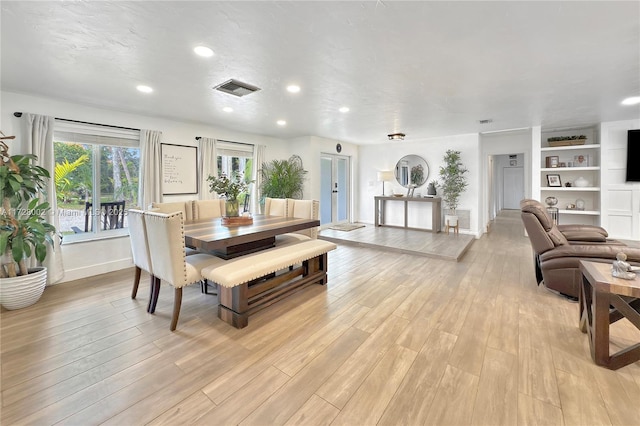 dining room featuring built in shelves and light hardwood / wood-style floors