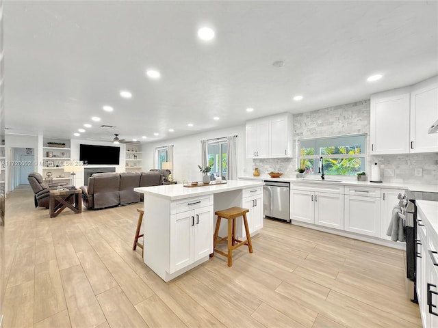 kitchen featuring white cabinetry, a kitchen bar, appliances with stainless steel finishes, a center island, and sink