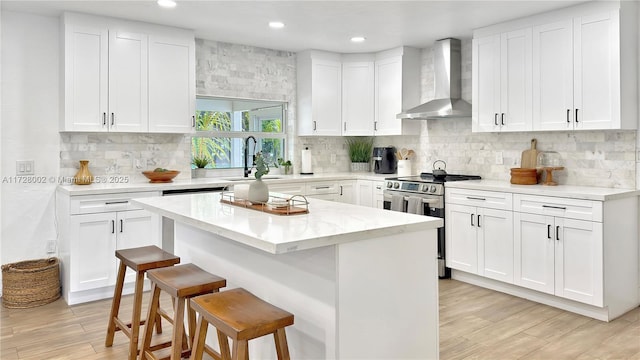 kitchen with sink, white cabinets, wall chimney exhaust hood, and stainless steel range with electric stovetop