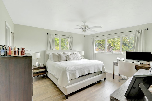 bedroom featuring ceiling fan, multiple windows, and light hardwood / wood-style floors