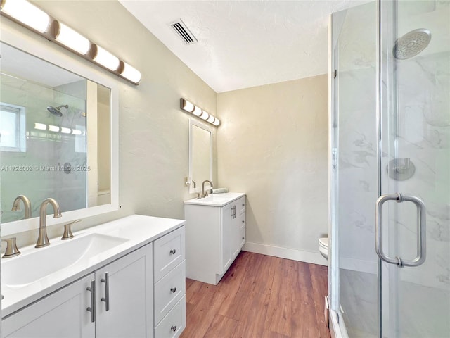 bathroom featuring toilet, a shower with shower door, hardwood / wood-style flooring, and vanity