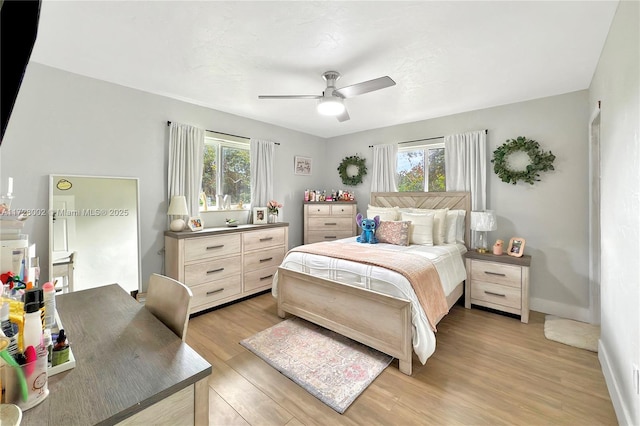 bedroom with ceiling fan, light hardwood / wood-style floors, and multiple windows