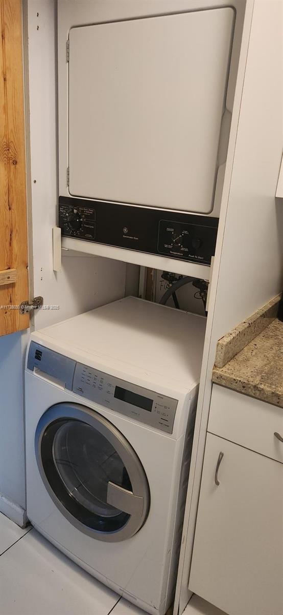 laundry room featuring stacked washing maching and dryer and light tile patterned floors